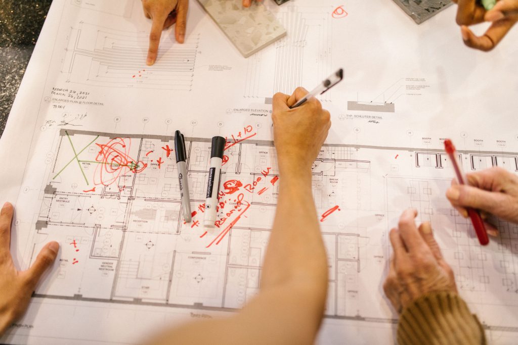 pexels photo 7490887 7490887 Team working together on architectural blueprints, marking plans with red ink.